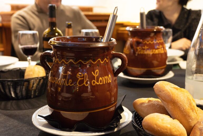 Orzas de barro del Restaurante El Lomo sirviendo cocido manchego tradicional con pan y vino en Albacete